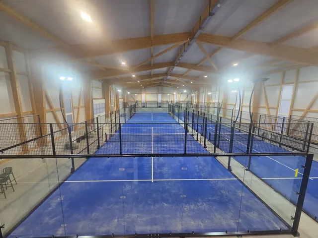 Blick über die Padel-Plätze unter dem Holzdachstuhl der Halle