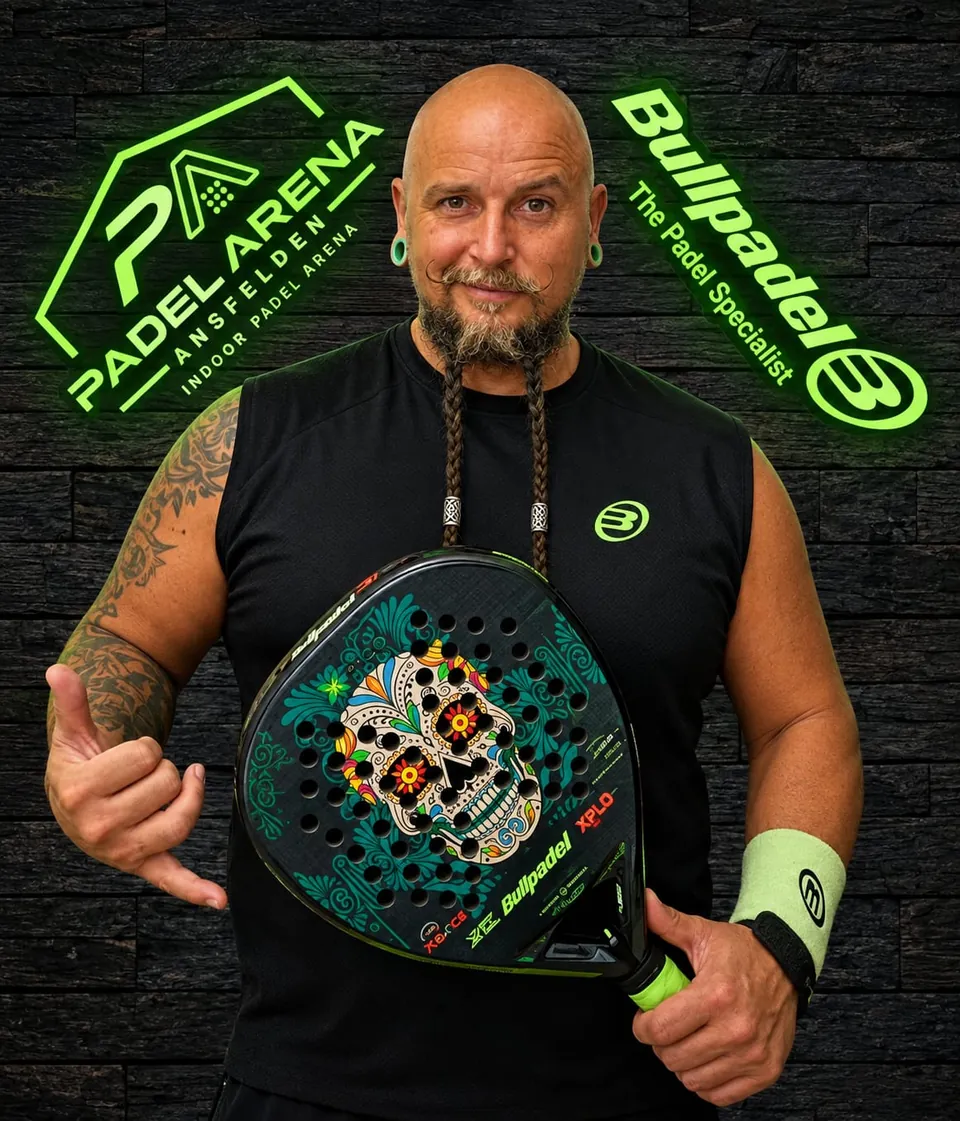 Padel-Trainer Markus Kofler (Kofi) im Bullpadel-Shirt mit Schläger vor dem Padel-Arena-Logo